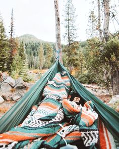 a hammock is set up in the middle of a wooded area with rocks and trees