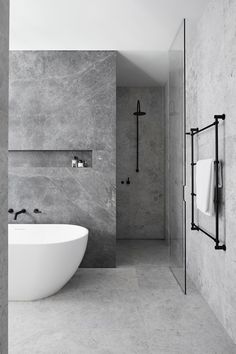 a white bath tub sitting in a bathroom next to a wall mounted shower faucet