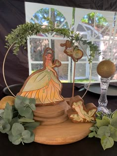 a table topped with figurines and greenery on top of a wooden stand