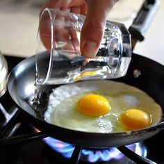 two eggs are being fried in a frying pan on the stove top with water