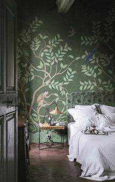 a bedroom with green wallpaper and white bedding, along with a bird painted on the wall