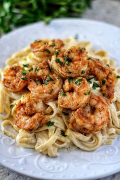 pasta with shrimp and parmesan cheese on a white plate next to green leaves