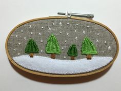 a hand embroidered christmas scene with three trees