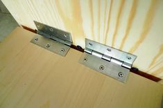 two stainless steel hinges on a wooden surface