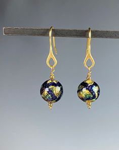 "Romantic and sultry Murano glass earrings that will captivate you! These artisan made glass beads from Murano, Italy are doused with colors of blue and green with genuine 18k gold foil within each bead! The beads hang on Vermeil gold ear wires. They hang 1.5 inches. A wonderful gift for any occasion and arrives in a standard gift box. ✨ Authentic Murano Glass: Each pair of earrings showcases the unparalleled beauty of Murano glass, renowned for its vibrant colors and intricate patterns. See our Elegant Glass Drop Earrings, Elegant Glass Dangle Jewelry, Elegant Dangle Glass Jewelry, Elegant Round Glass Earrings, Elegant Czech Glass Jewelry With Matching Earrings, Elegant Nickel Free Glass Earrings, Elegant Nickel-free Glass Earrings, Unique Gold Glass Earrings, Elegant Gold Glass Earrings