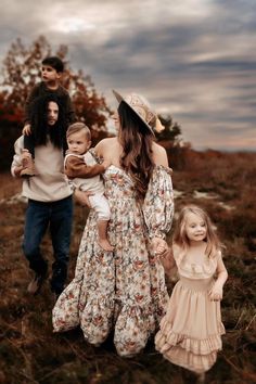 a woman and two children walking through a field