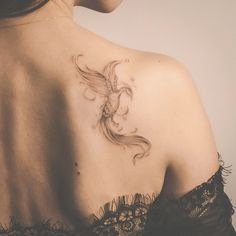 the back of a woman's shoulder with a goldfish tattoo on her left shoulder