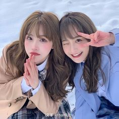 two young women posing for the camera in front of snow covered ground with their hands together