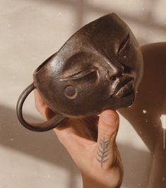 a person holding up a coffee mug shaped like a buddha head with their face on it