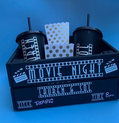 a black box with two cups and some movie tickets in it on a blue background