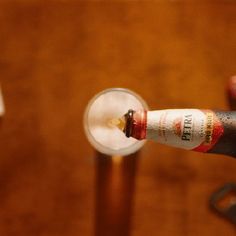 a close up of a person holding a wine glass with a bottle in the background