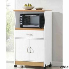 a microwave oven sitting on top of a white cabinet next to a bowl of fruit