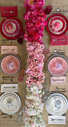 the table is set with pink and white plates, silverware, and floral centerpieces