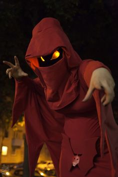 a person in a red costume with an evil look on their face and hands, holding out two fingers