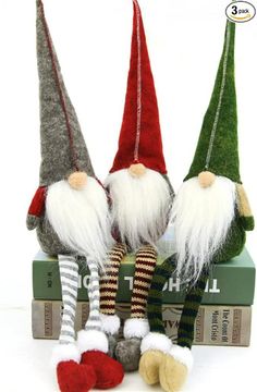 three christmas gnomes sitting on top of books