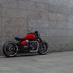 a red and black motorcycle parked in front of a wall