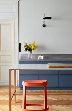 an orange stool sits in front of a kitchen island with blue cabinets and counter tops