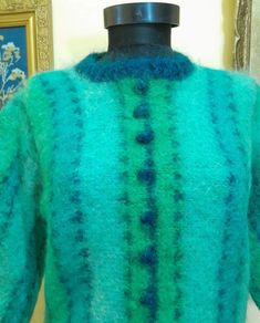 a green and blue sweater sitting on top of a mannequin