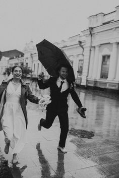 a man and woman running in the rain with an umbrella