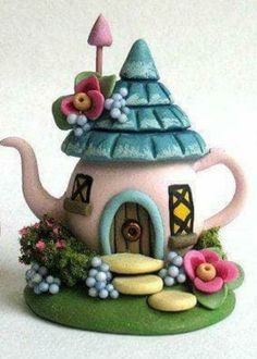 a teapot shaped like a house with flowers on it