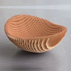 a wooden bowl sitting on top of a gray floor next to a white wall and carpet