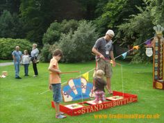 a man and two children are playing in the grass with an amusement park game set