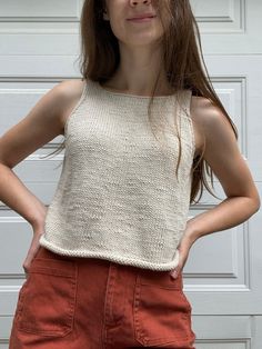 a woman standing in front of a garage door with her hands on her hips and looking at the camera