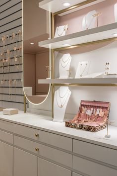 an assortment of jewelry on display in a store with gold trimmings and pink walls