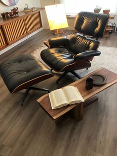 an empty living room with black leather chairs and a book on the coffee table in front of it