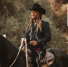 a man with dreadlocks sitting on top of a horse