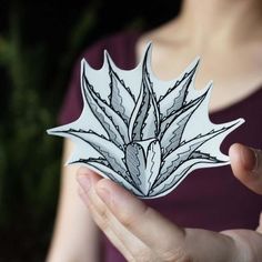 a woman holding up a paper cut out of a plant