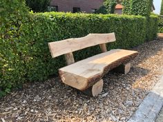 a wooden bench sitting in front of a hedge