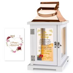 a small white box with a rose on it next to a greeting card and an ornament