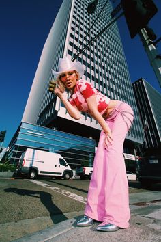 a woman standing on the side of a road next to a tall building