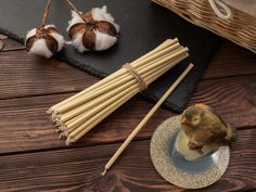 two small birds sitting on top of a plate next to chopsticks and cotton balls