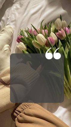 a bouquet of tulips on a bed next to a pair of white gloves