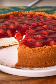 a cheesecake with strawberries on top sits on a white plate and is ready to be eaten