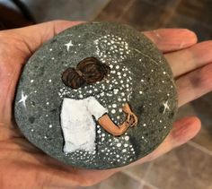 a hand holding a rock with a painting on it