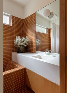 a bathroom with a sink, mirror and bathtub next to a plant in a vase