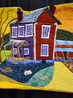 a quilted wall hanging with a house on it