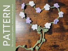 a crocheted heart with flowers on it and the words pattern written in white