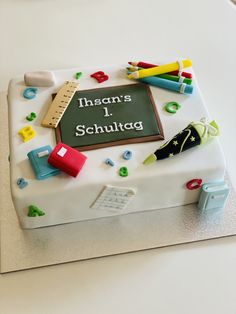 a cake that is sitting on top of a table with writing and school supplies around it