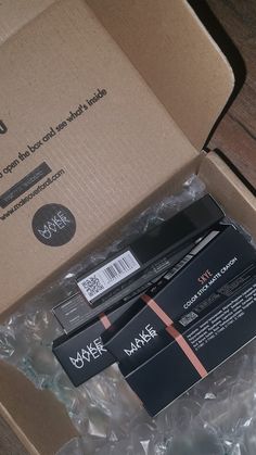 an opened box containing two mascaras and some plastic wrap on the inside of it