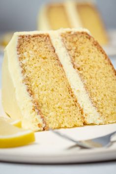 a slice of cake on a plate with a fork and lemon wedge next to it