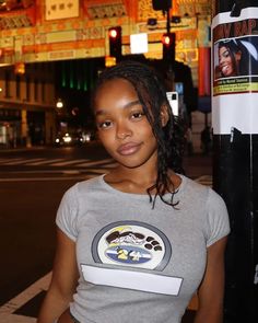 a woman standing next to a pole on a city street