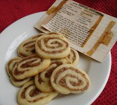 cinnamon roll cookies on a white plate next to a red tablecloth with an old recipe book