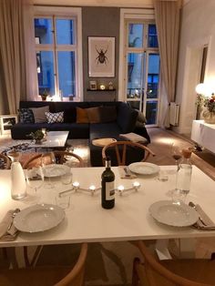 a living room filled with furniture next to a table covered in plates and wine glasses