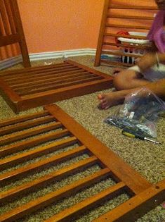 two children sitting on the floor next to a bed frame