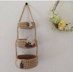 there is a crocheted hanging basket on the wall next to a flower pot