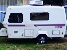 an rv parked in the grass next to a building